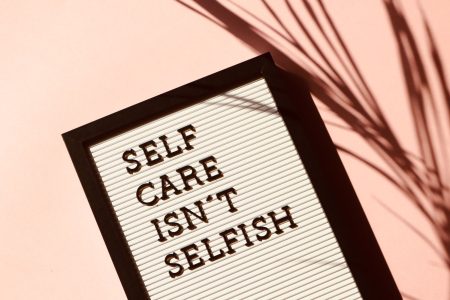 Tafel mit der schwarzen Aufschrift "Self care isn't selfish"